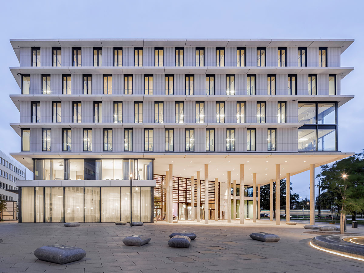 Konzernzentrale Enercity Abendansicht der weißen Gebäudefassade mit Sitzmöbeln und Lichtern außen vor Himmer zu blauer Stunde
